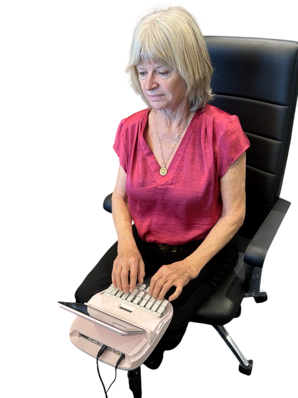 A woman sits at a desk with a laptop, while a man stands behind her holding papers in a classroom setting. The environment appears to be set up for a presentation or lecture. and captioning services